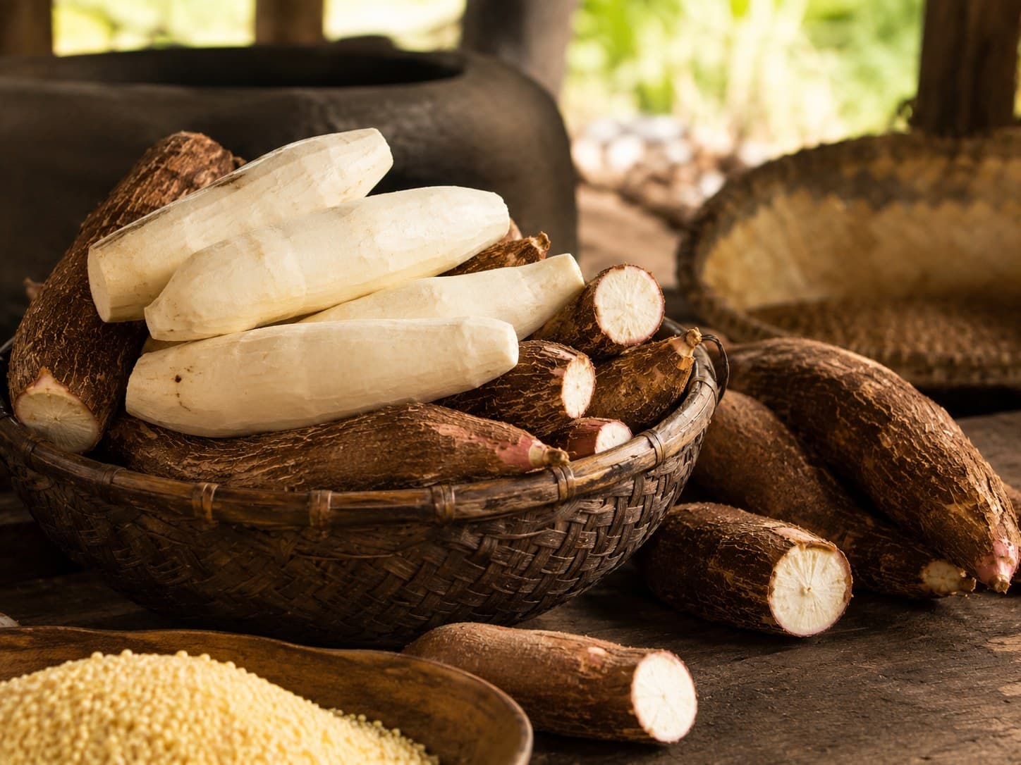 Cesto com mandioca descascada e raízes inteiras na área de produção